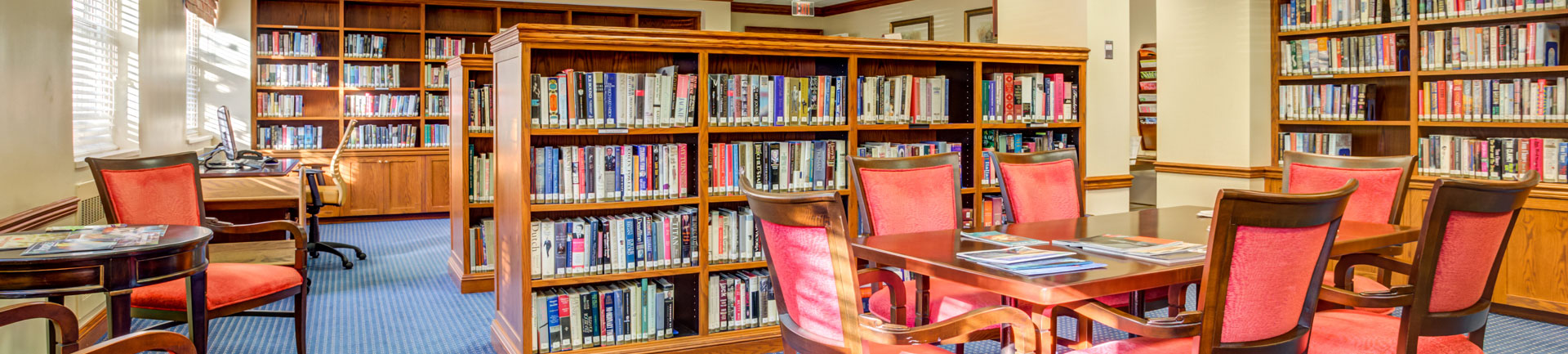 a library inside of a senior living community with tables and chairs to sit at