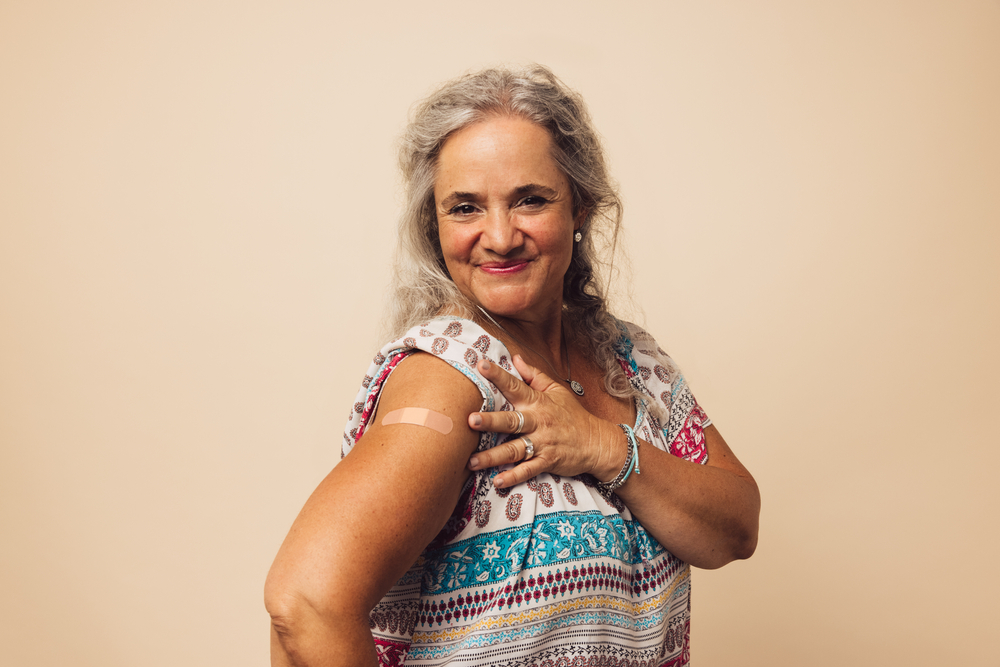 Senior woman rolls up her sleeves to show the band aid of where she got vaccinated