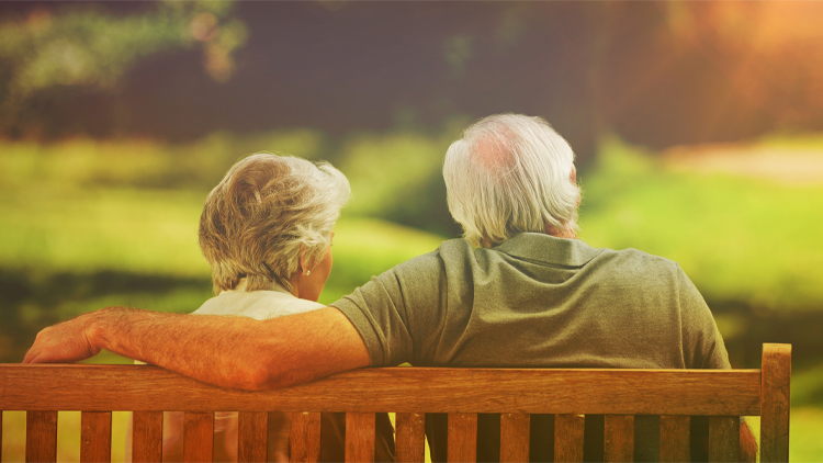 a senior couple sitting on a bench outside