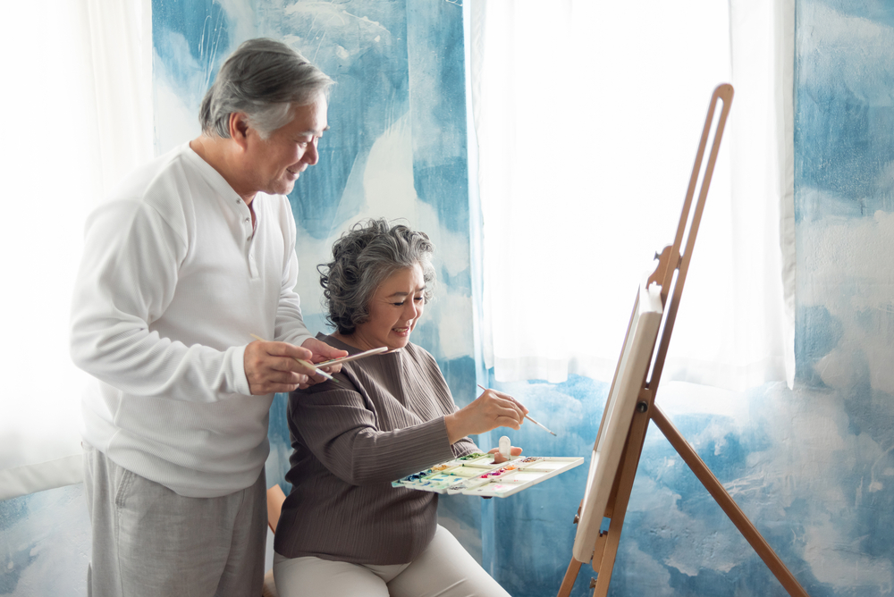An older couple work on an oil painting together