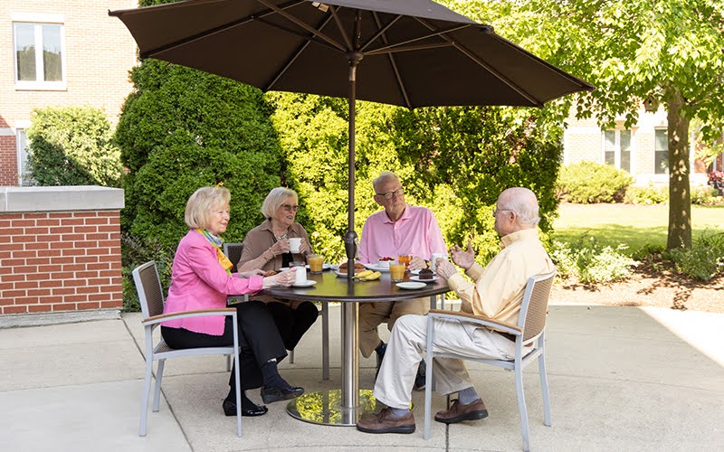 Group of residents enjoying a meal outdoors together at Lake Forest Place