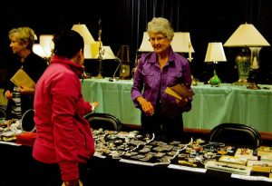 senior woman at a table selling trinkets and miscellaneous items