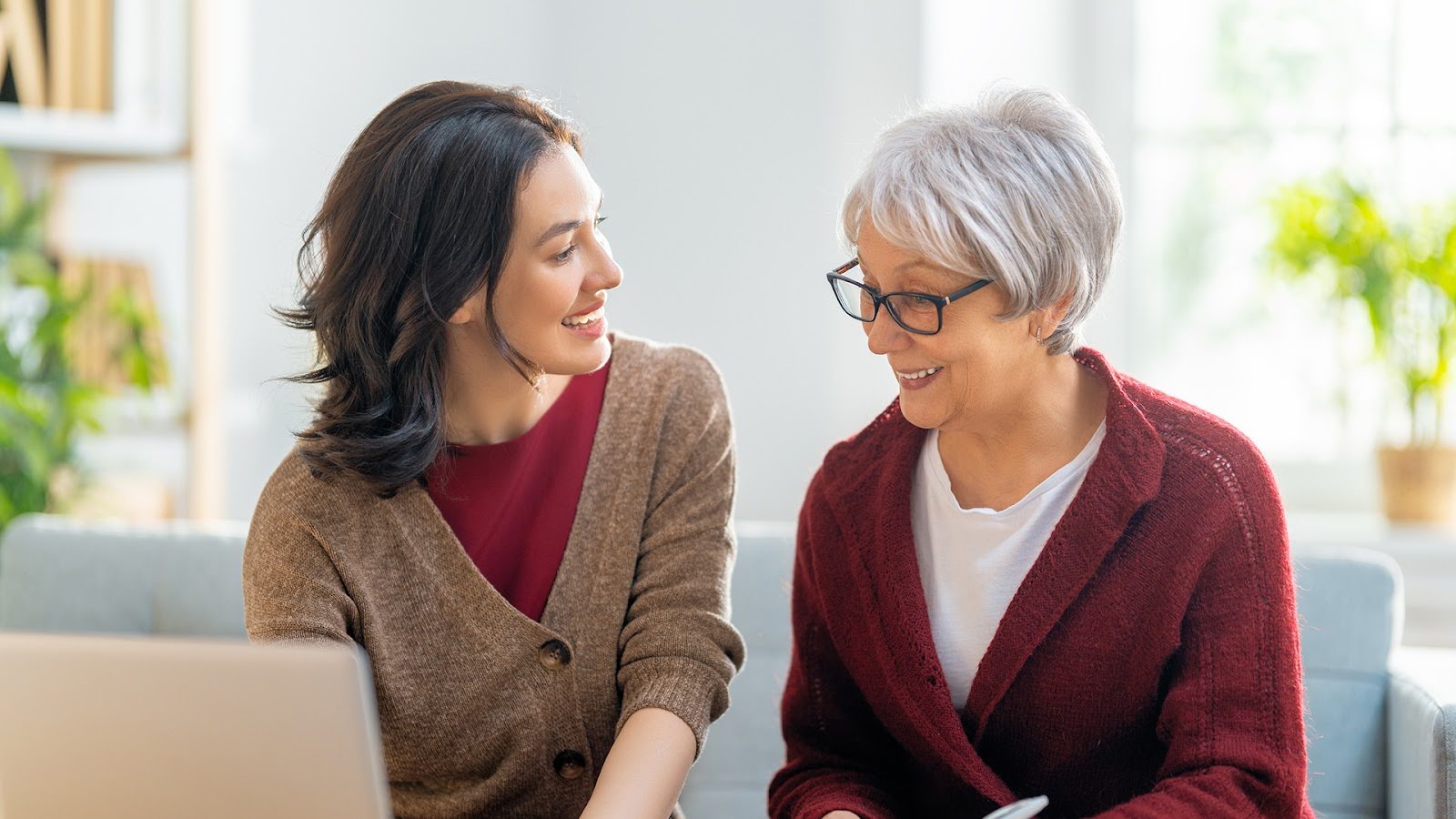 Senior woman sitting on a sofa with her adult daughter discussing senior living