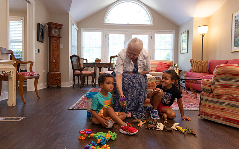 Senior woman playing with her young grandchildren in her apartment at Westminster Place