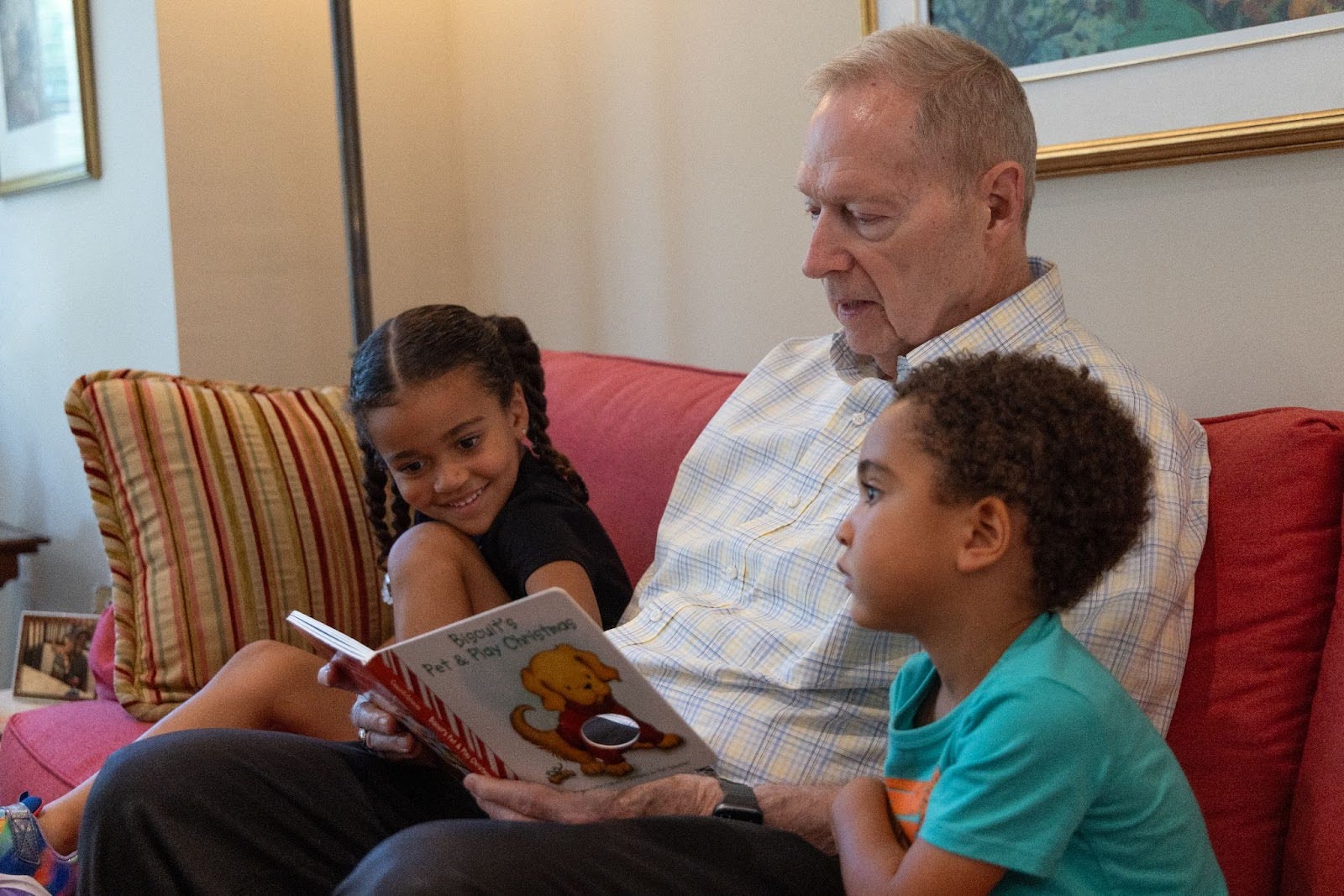 Resident of Westminster Place reading a book to his grandchildren in his apartment home