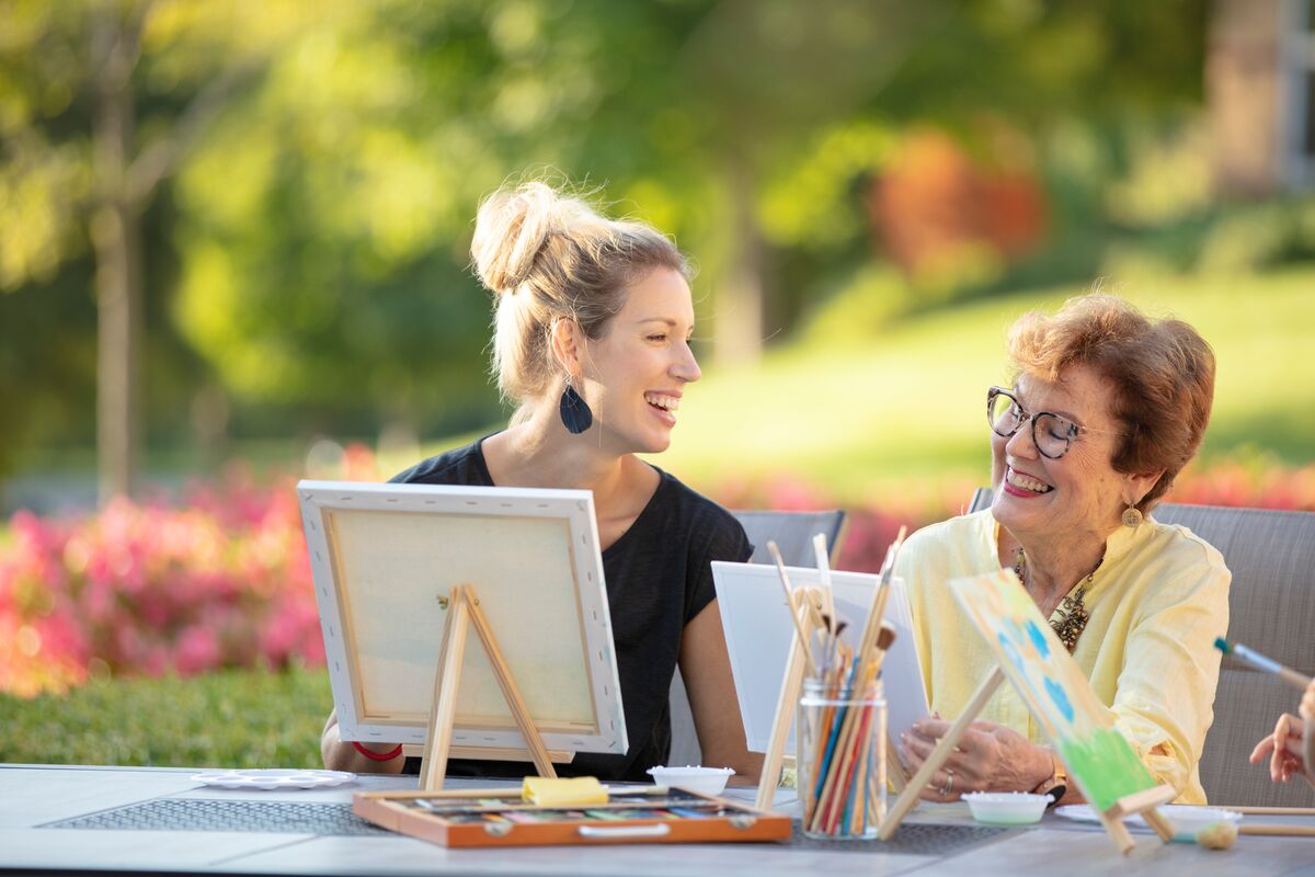 College student happily painting with a senior citizen 
