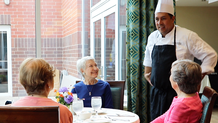 a group of senior women talking to the chef at their senior living community