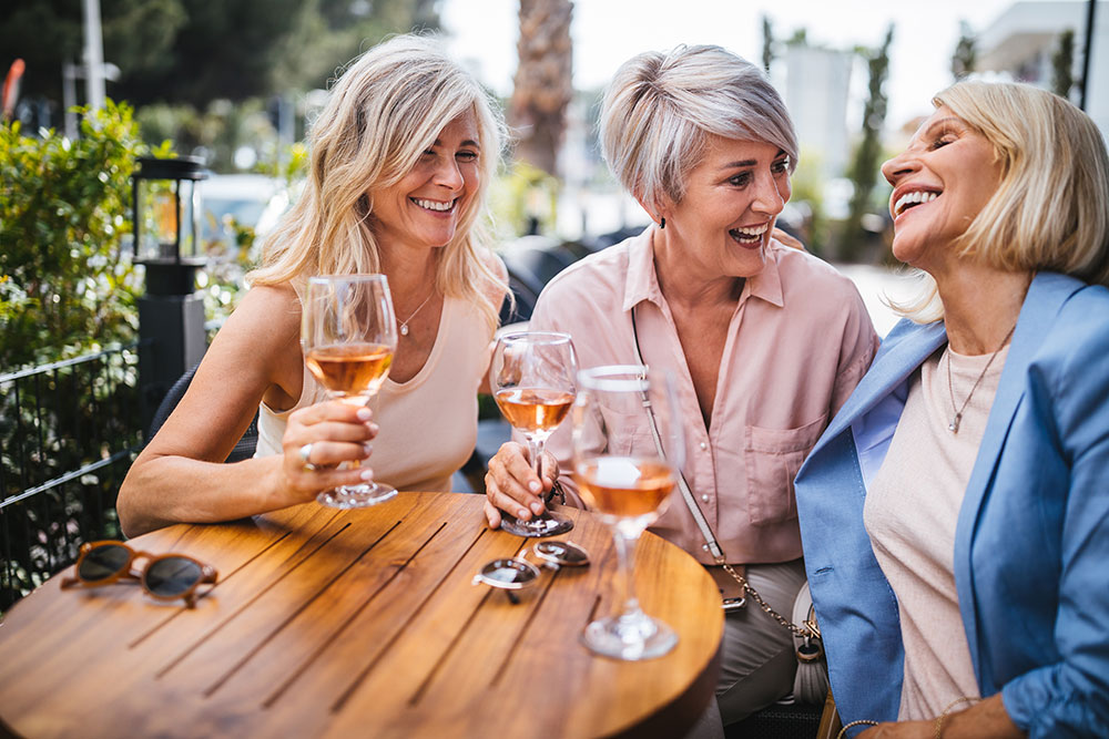 3 senior women sipping wine at an outdoor restaurant table