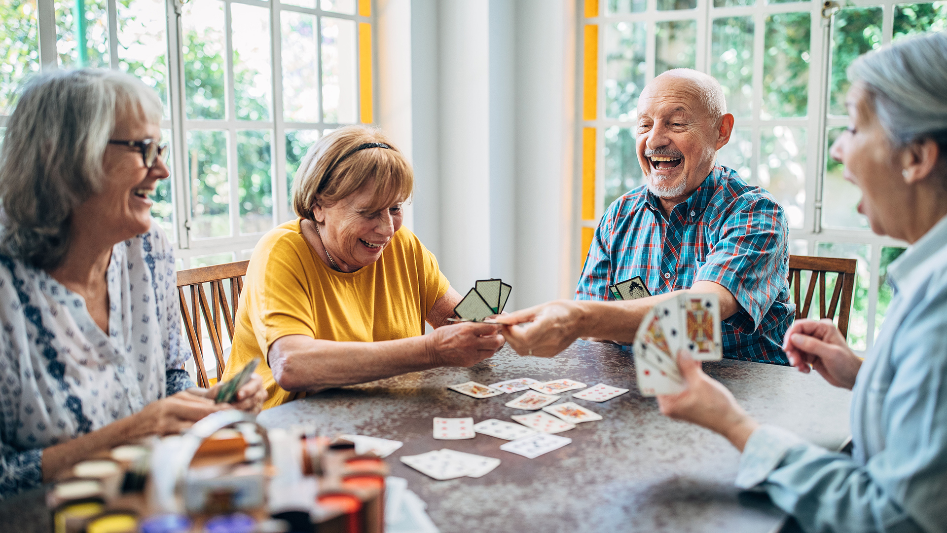 Group of senior friends playing cards and laughing together